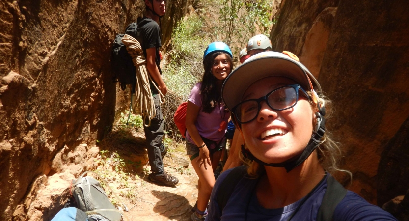 A small group of people smile for a photo between two canyon walls.